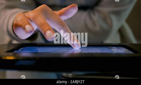 Woman hand using touchscreen display of floor standing black tablet kiosk Stock Photo