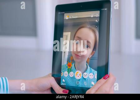 Woman using Snapchat multimedia messaging app with face mask on tablet Stock Photo