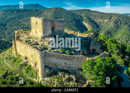 Aerial view of Jalance castle in Spain on a hilltop from the 12th century consisting of inner castle yard, irregular shape outer wall with round tower Stock Photo