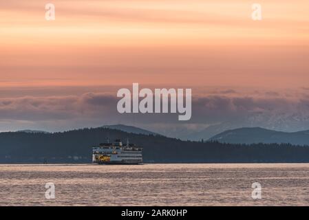 Washington State Ferry crossing Puget Sound at twilight with Olympic Mountains beyond, from Seattle, Washington Stock Photo