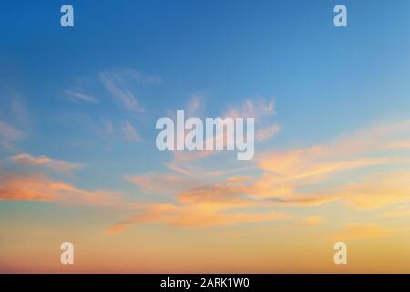 Golden sunset clouds in a clear blue sky. Scenic dusk skyscape. Twilight paradise sky. Calm heaven background. Beauty in nature. Stock Photo