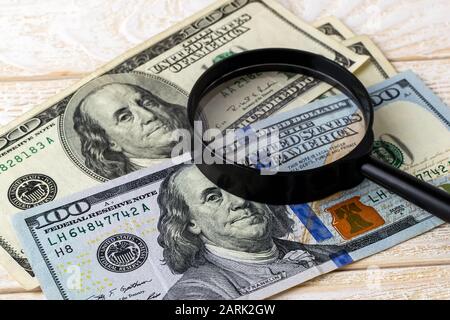 Magnifier on new and old dollar banknotes on a white wooden surface. Check the authenticity of money. Wealth, poverty and counterfeiting money concept Stock Photo