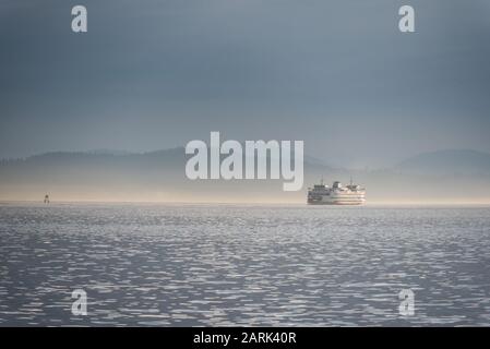 Washington State Ferry crossing Puget Sound at twilight with Olympic Mountains beyond, from Seattle, Washington Stock Photo