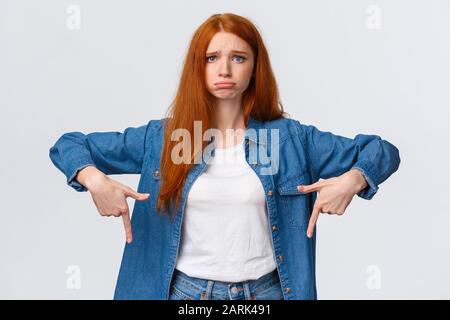 So sad. Upset and gloomy cute redhead teenage girl asking permission participate student trip abroad, feeling regret and jealousy, looking camera Stock Photo