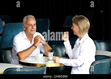 Mature married couple: A lovely mature married couple at a cafe having coffee together and talking, shot in color. Stock Photo