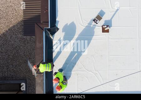 Aerial shot of construction workers on flat rooftop Stock Photo
