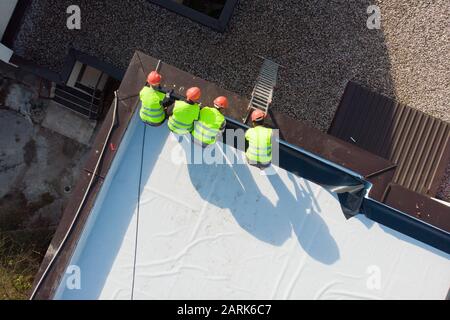 Aerial shot of construction workers on flat rooftop Stock Photo