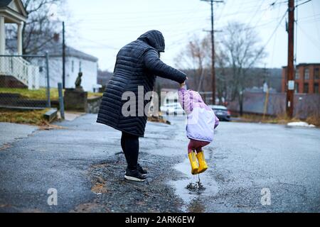 A mother and child having fun jumping in puddles. Stock Photo