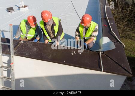 Aerial shot of construction workers on flat rooftop Stock Photo