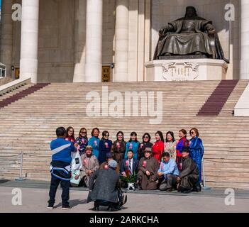 People in formal & traditional dress posing by Genghis Khan statue for photo, Sükhbaatar Square, Ulaanbaatar, Mongolia Stock Photo