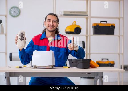 The young male contractor repairing toaster at workshop Stock Photo