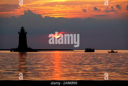 Silhouette of the lighthouse and boats during the sunset at Cape Henlopen State Park, Lewes, Delaware, U.S.A Stock Photo