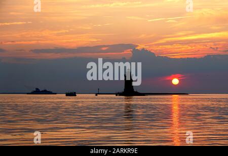 Silhouette of the lighthouse and boats during the sunset at Cape Henlopen State Park, Lewes, Delaware, U.S.A Stock Photo