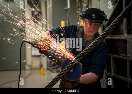 NORFOLK (Dec. 18, 2019) Airman Bella Villareal, from San Antonio, assigned to USS Gerald R. Ford's (CVN 78) air department, grinds down a weld on an arresting gear cable during a cable re-reave evolution. Ford is currently in port after completing a successful independent steaming exercise. (U.S. Navy photo by Mass Communication Specialist 3rd Class Joshua Murray) Stock Photo