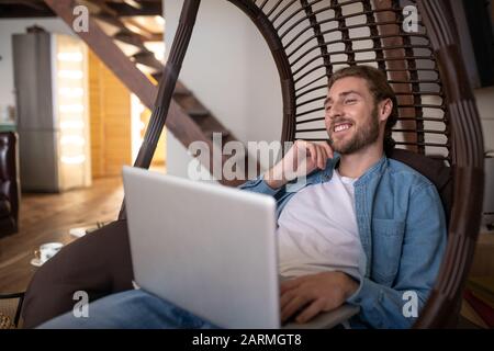 Relaxed man chatting with friend via video call Stock Photo