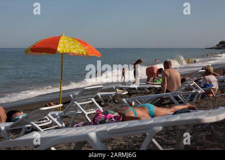 beach parasol, woman laying, tourism travel, dry grass, alushta crimea, senior couple, seaside resort Stock Photo