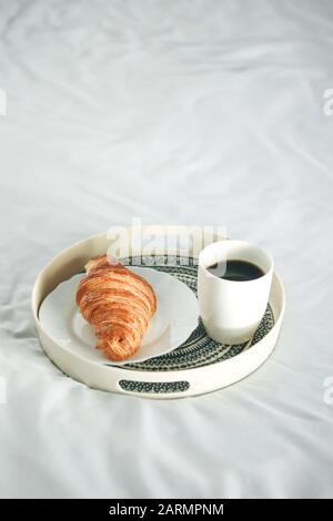 Morning coffee with a croissant on a tray on the bed Stock Photo