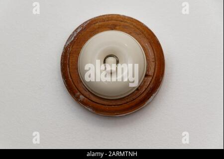 A round light switch is backed by wood and in the on position Stock Photo