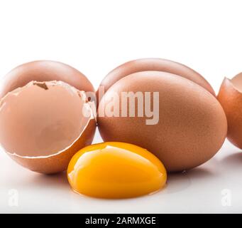 Chicken eggs and broken egg with yolk isolated on white background. Stock Photo