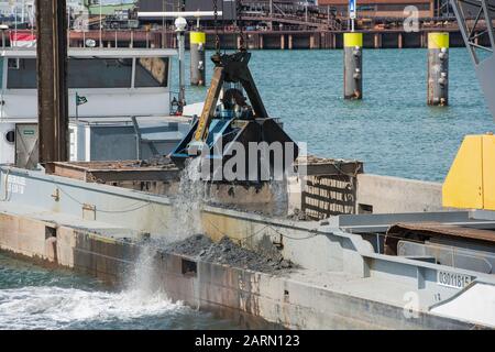 Rotterdam, Netherlands - July 30, 2019; Dredger vessel grabbing harbor sludge with a grab bucket in the harbor of Rotterdam Stock Photo