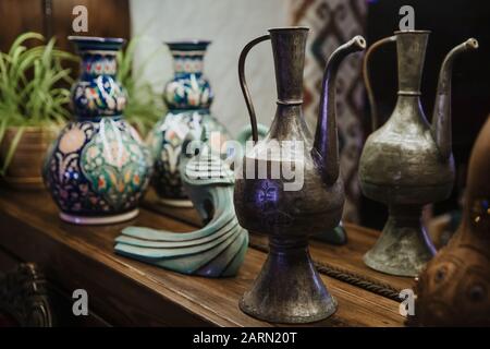 An ancient copper decanter and an ornate clay jug stand on a shelf. Stock Photo