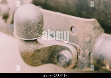 Old Tow Hitch for towing a trailer. A dirty rusty trailer hitch is mounted on the machine. Rear power bumper. Close-up. Selective focus. Stock Photo