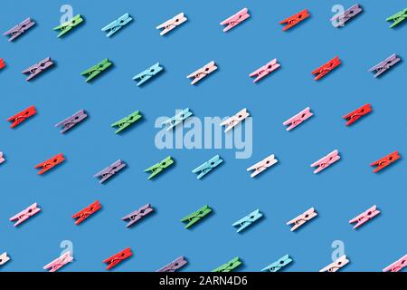 Horizontal laundry pattern from colorful clothes pins on a blue background. Top view. Stock Photo