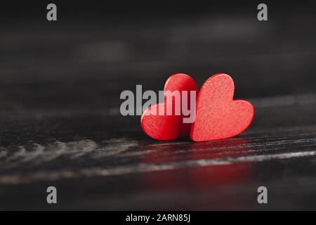 Two decorative hearts on dark wooden background. Stock Photo