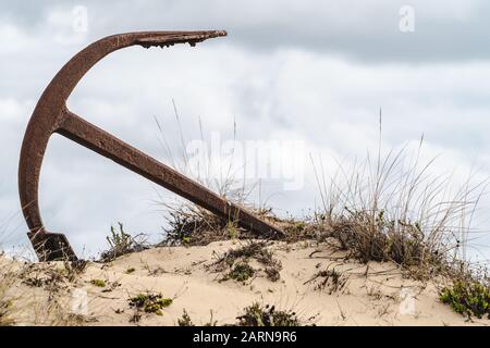 Rusty old anchor on the beach at the Anchor Cemetary at Praia do Barril beach, in Tavira, Algarve, Portugal Stock Photo