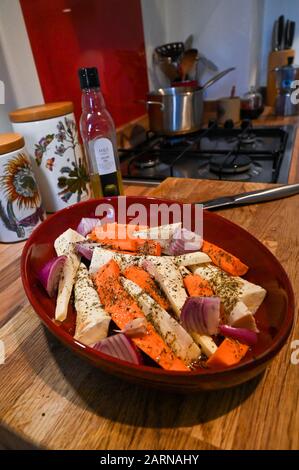Carrots onions parsnips and garlic ready to be oven roasted with herbs for winter roast lunch  Photograph taken by Simon Dack Stock Photo