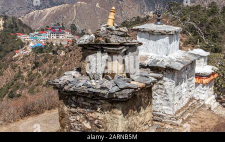 Buddhist Chorten with ancient Mani Stone with engraved Sanskrit sacred mantra 'Om Mani Padme Hum' on the background of Tengboche Monastery in Himalaya Stock Photo