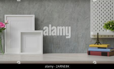 Close up view of stylish workplace with copy space, mock up frames and decorations on marble desk with shelf on grey loft wall background Stock Photo