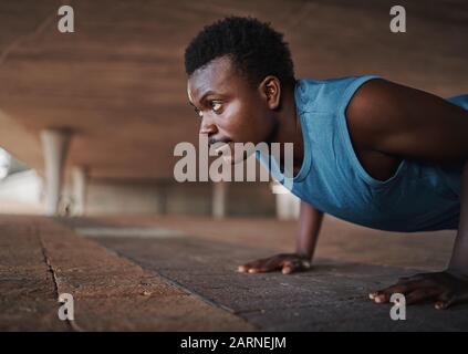 Young african american sports physique man doing push-ups on the pavement at outdoors