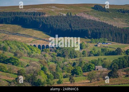 Near Cowgill, Cumbria, England, UK - May 16, 2019: A train passing the Dent Head Viaduct on the Settle-Carlisle Railway line Stock Photo