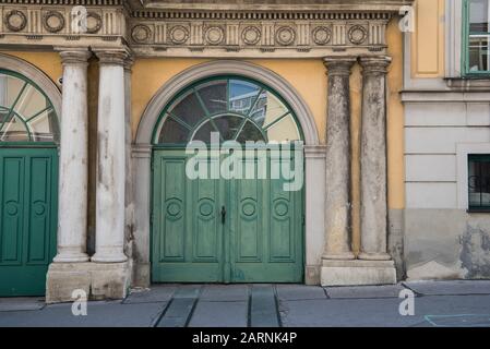 Old wooden green door and antique yellow limestone wall for an antique urban background Stock Photo