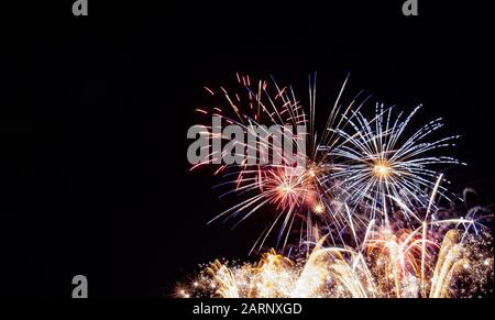 Multiple starburst fireworks over gold sparkling fireworks photographed against a black sky on the Fourth of July in Minnesota Stock Photo