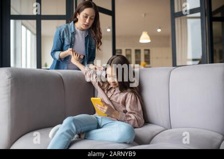 Sly little naughty girl and mom in the room. Stock Photo