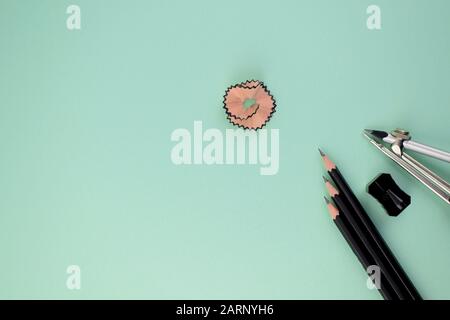 three black pencils along side a black sharpener and a pencil compass attached to a silver pencil pointing at a pink pencil shaving in the center Stock Photo