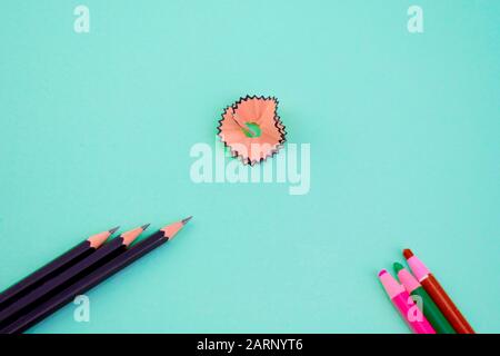 bunch of dark black wooden pencils which r sharpened and three different colored pencil crayons pointing at a pink pencil shavings from different dire Stock Photo