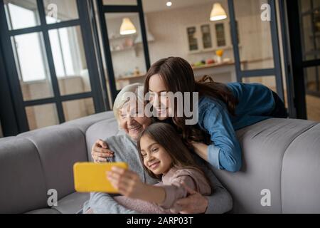 Hugging and taking selfie girl, mom and grandmother. Stock Photo