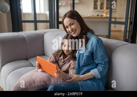 Mom with daughter sitting on the sofa at home. Stock Photo