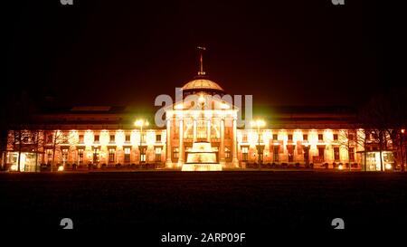 Panoramic view of Wiesbaden Kurhaus casino and fountain illuminated at night. Golden night scene as seen from the Bowling green lawn and park. Stock Photo