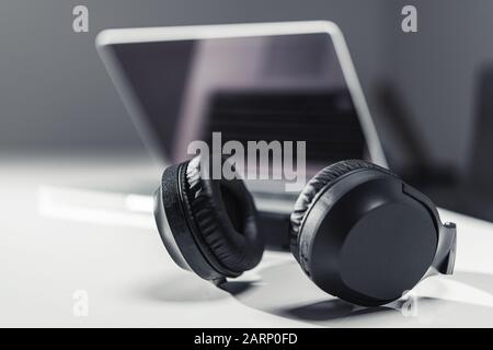 Modern Laptop Computer and Large Professional Wireless Headphones. Online Streaming Technologies Concept. Stock Photo