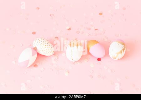 Pink and gold decorated eggs with festive confetti on a pink background, top view Stock Photo