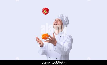 Excited Chef Man Juggling Sweet Peppers Standing In Studio, Panorama Stock Photo