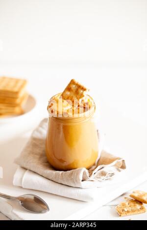 Homemade natural paleo nut peanut cashew creamy butter in glass jar and spoon on white background.Copy space, vertical orientation Stock Photo