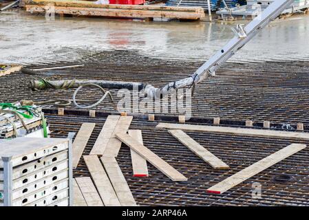 Pouring cement to make reinforced concrete over rebar on a working construction site during a new building project Stock Photo