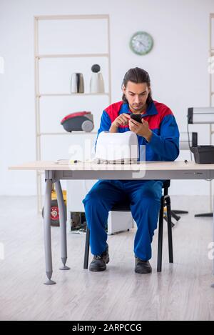 The young male contractor repairing toaster at workshop Stock Photo
