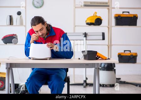 The young male contractor repairing toaster at workshop Stock Photo