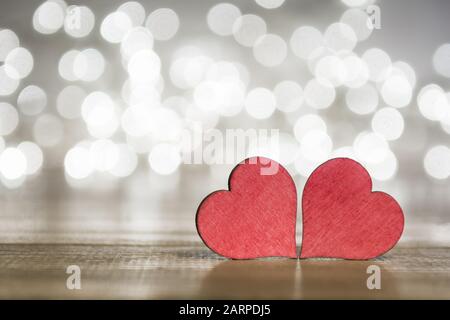 Two red hearts on wooden surface with bokeh lights background, on a valentines day concept Stock Photo